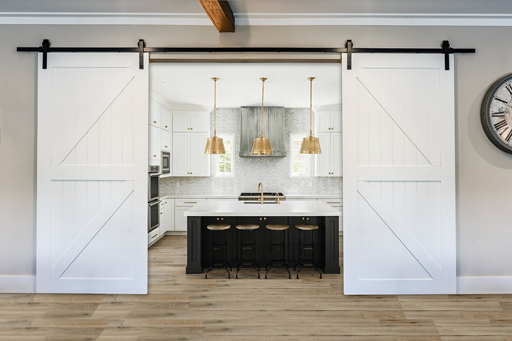 White barn doors in a contemporary interior framing an upscale kitchen